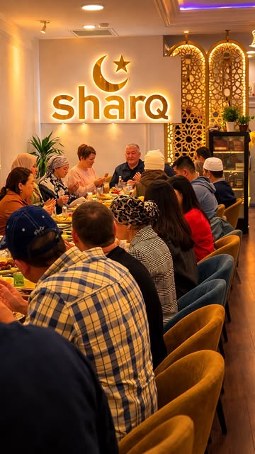 The dining room under the gold Sharq sign, full of guests at long tables