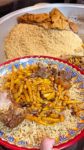 A wide platter of plov — rice, lamb and yellow carrots — served on a painted lyagan