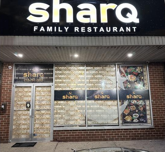 The lit Sharq Family Restaurant storefront on Philmont Avenue at night